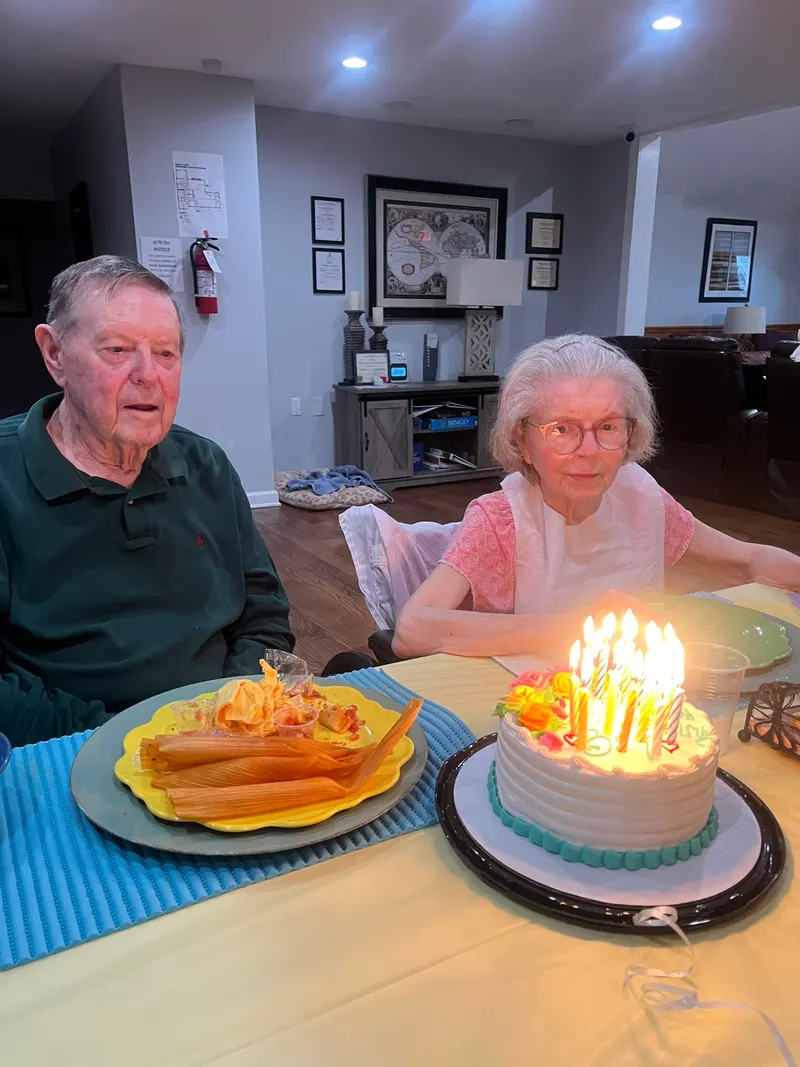 A resident smiling at her lit birthday cake.