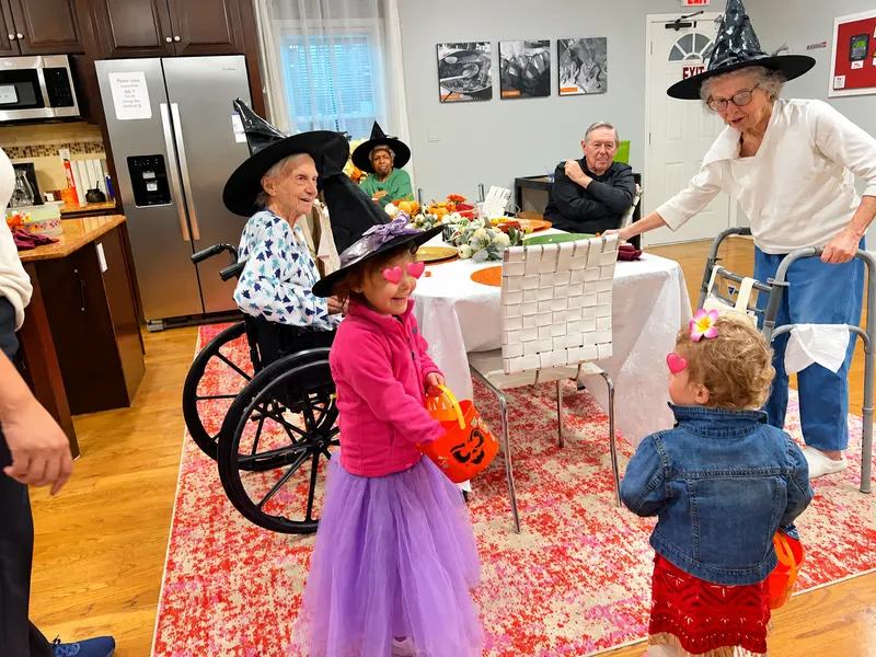 A resident in a witch hat handing out candy to a young trick-or-treater.
